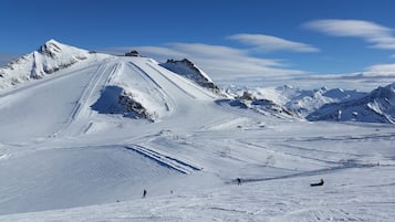 A snow-covered mountain with ski slopes, ski lifts, and a clear blue sky.