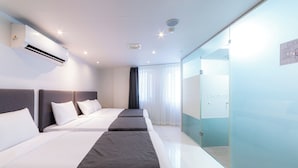 Ein Hotelzimmer mit zwei Betten, einer Glastrennwand und einer Klimaanlage.