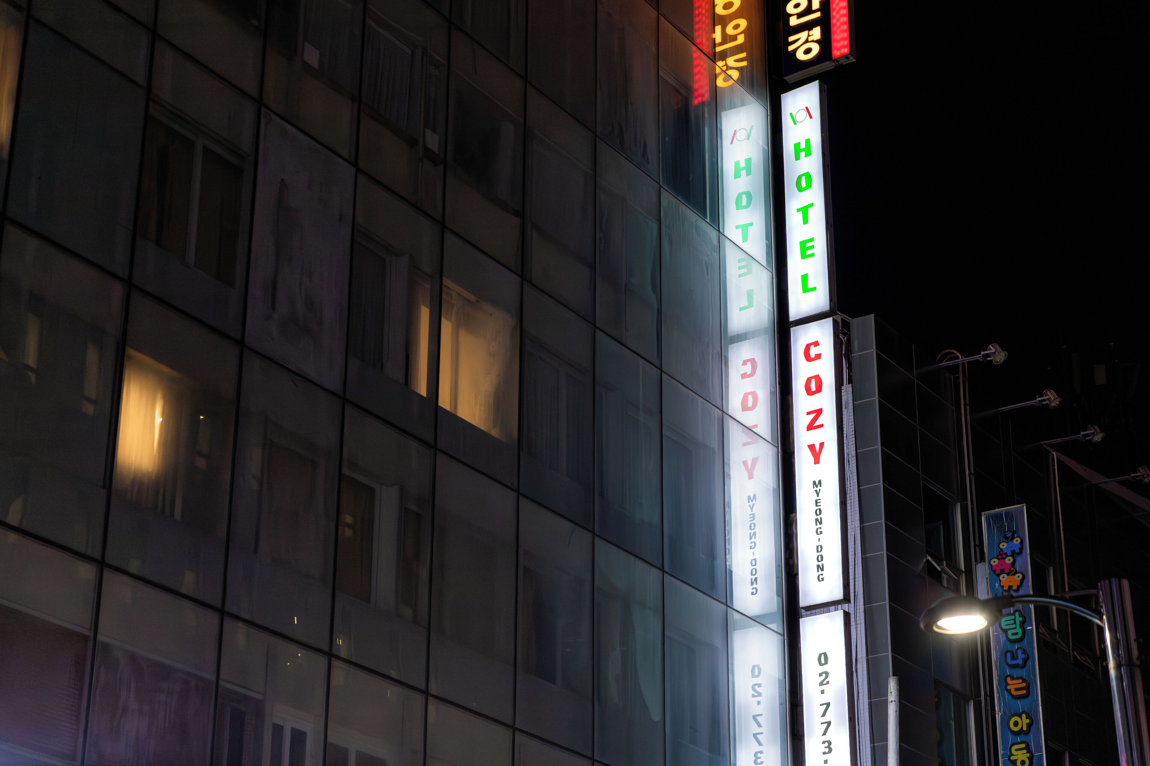 Un hôtel doté d’une enseigne lumineuse, notamment d’un néon indiquant le mot « HÔTEL » et d’un autre néon indiquant le mot « COSY ».