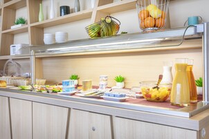 A buffet setup with various food items, including fruits, salads, and beverages.