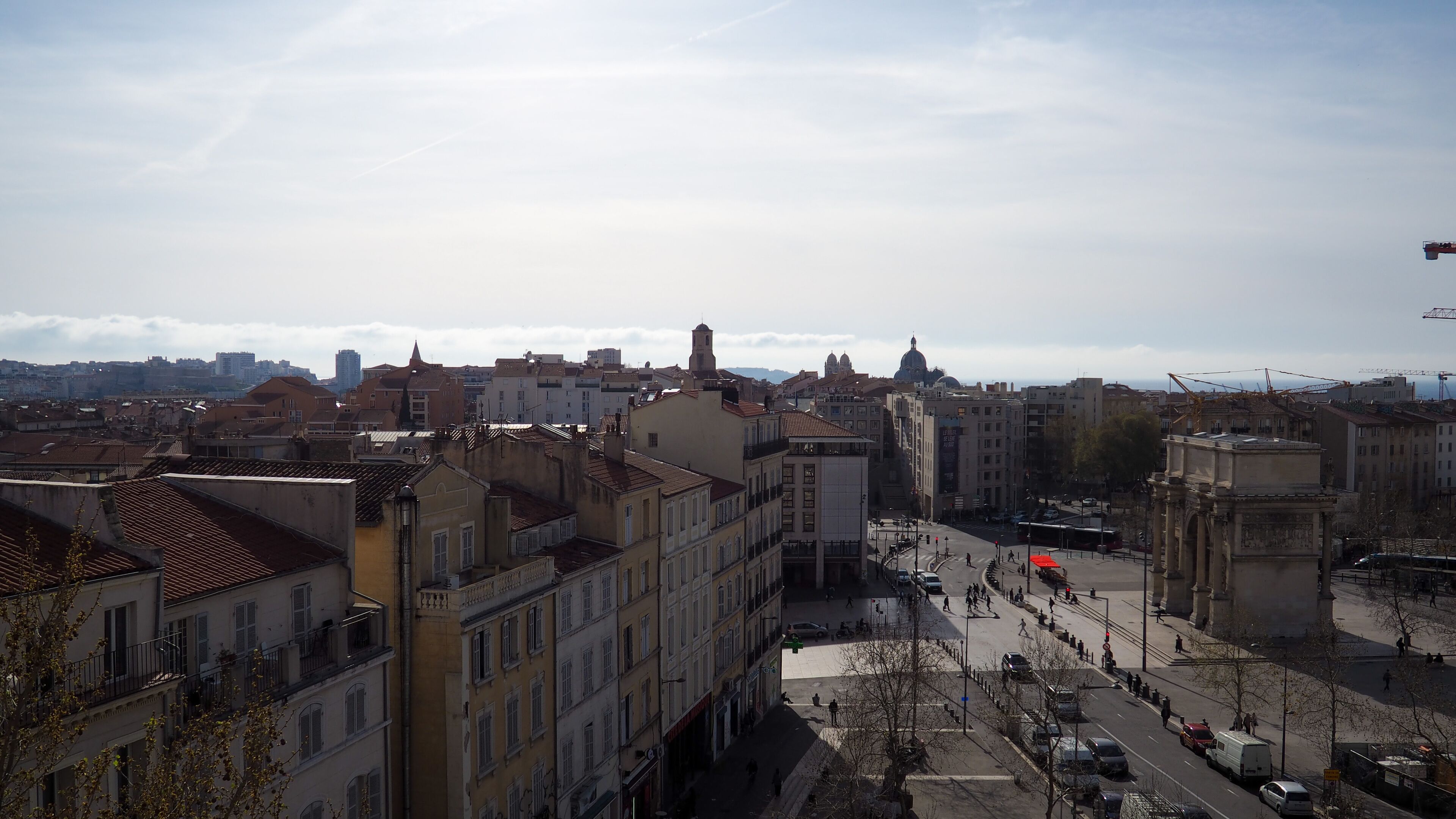 A cityscape with historic buildings, a central square, and a distant view of mountains.