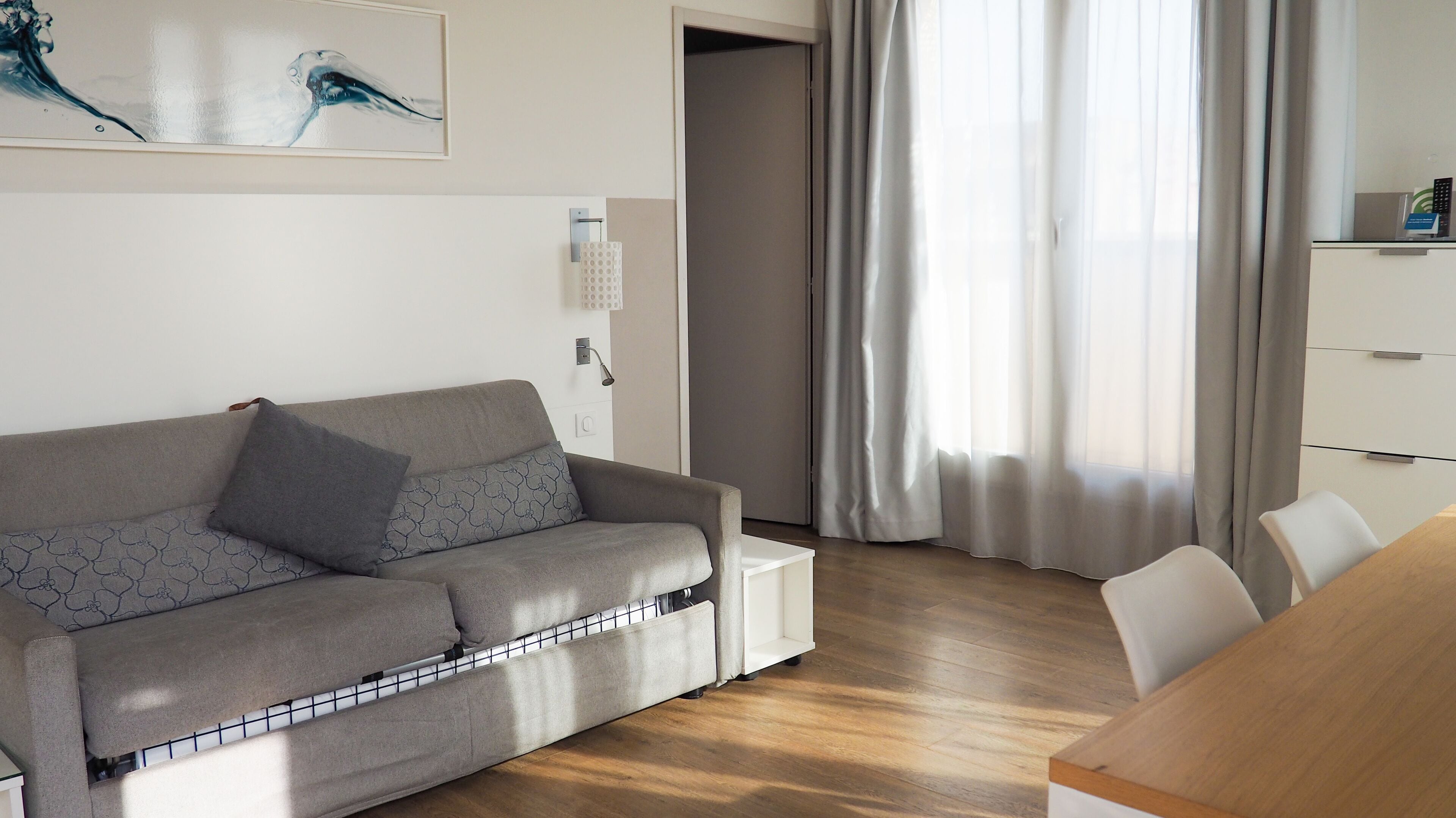 Un salon moderne avec un canapé gris, une table basse en bois et un meuble blanc.