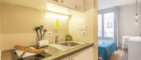 Une cuisine moderne équipée d’un four à micro-ondes encastré, d’un évier et d’une petite plante.