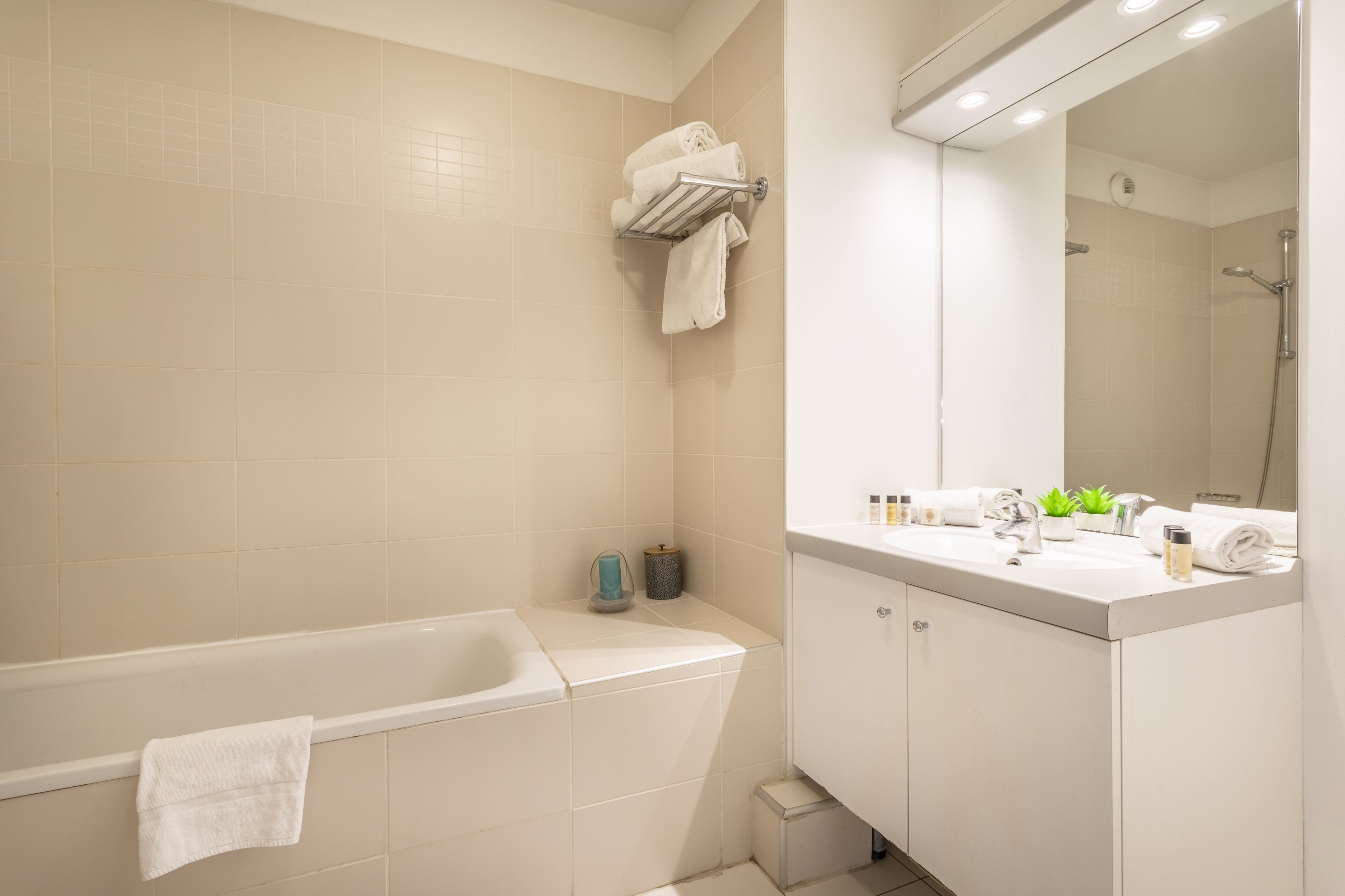 A modern bathroom with a bathtub, a vanity with a mirror, and a towel rack.
