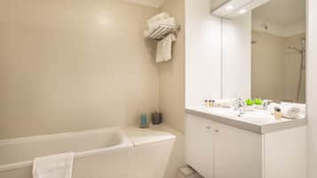 Un baño moderno con bañera, tocador con espejo y un perchero para toallas.