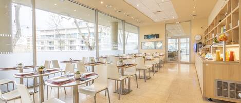 Un café espacioso con mobiliario moderno, ventanas amplias y vistas a la ciudad.