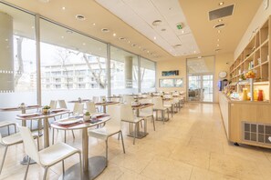 Ein großzügiges Café mit zeitgenössischer Einrichtung, großen Fenstern und Blick auf die Stadt.