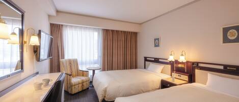 Een hotelkamer met twee bedden, een bureau, een stoel, een televisie en een klein tafeltje.