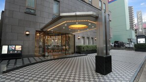 A hotel entrance with a glass facade, a checkered floor pattern, and a prominent 'P' sign indicating parking.