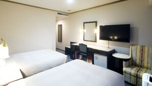 A hotel room with two beds, a desk with a chair, a television, and a small table.