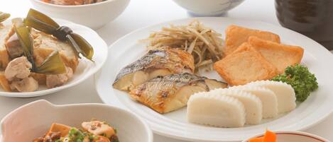 A variety of dishes including fish, tofu, and rice, served on a white table.