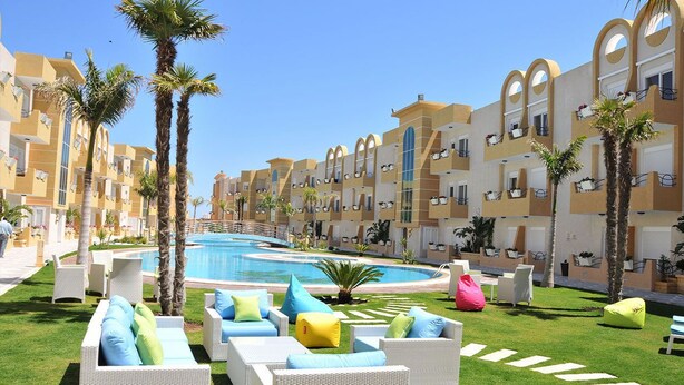 A resort with a swimming pool, lounge chairs, and palm trees. - The Dunes Golf & Spa Resort (Port El Kantaoui)