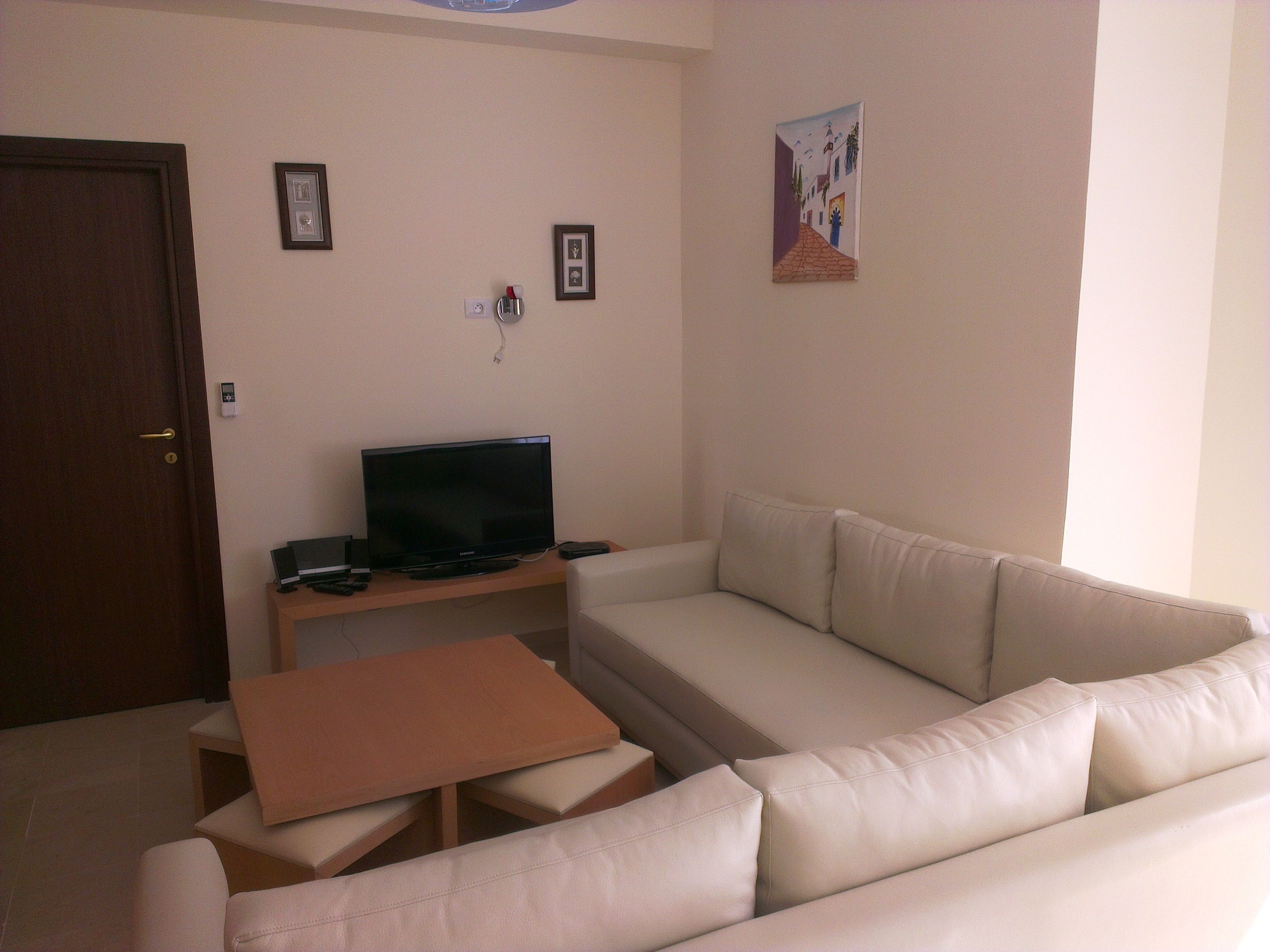 A living room with a sofa, a coffee table, and a television on a stand.