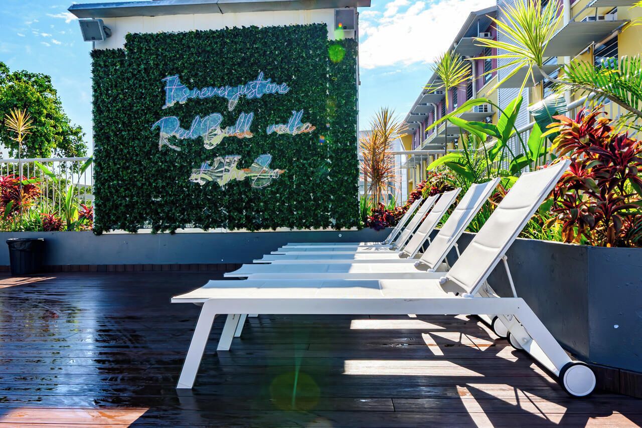A pool area with lounge chairs and a wall with greenery and text.