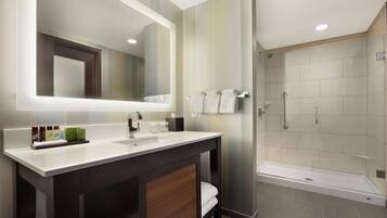 A modern bathroom with a large mirror, two sinks, and a shower area.