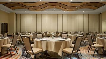 A conference room with round tables, chairs, and a patterned carpet.