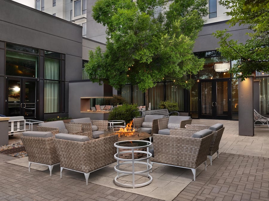 An outdoor seating area with wicker furniture and a central fire feature.