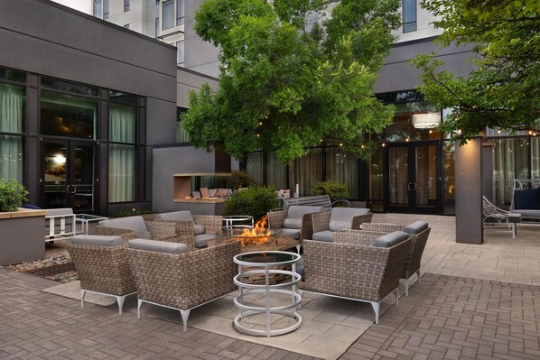 An outdoor seating area with wicker furniture and a central fire feature.