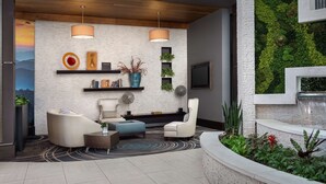 Una sala de estar moderna con chimenea, asientos cómodos, televisor y una pared verde con plantas.