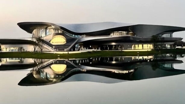 A modern architectural building with a unique curved design, large windows, and a reflection in the water. - Tianyue Hotel (Chengdu)