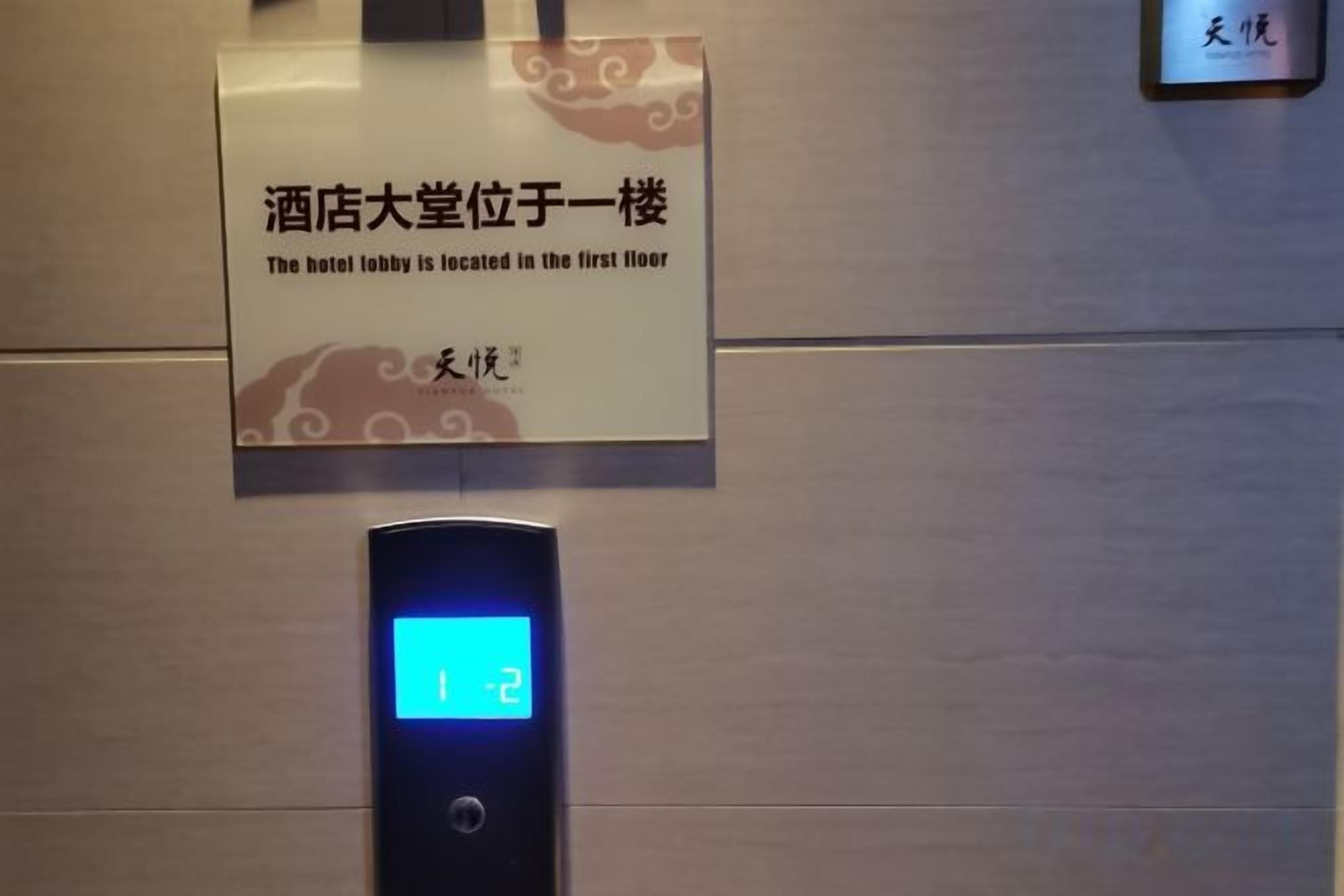 A digital elevator display with the number 12, a sign indicating the hotel lobby is on the first floor, and a metallic wall.