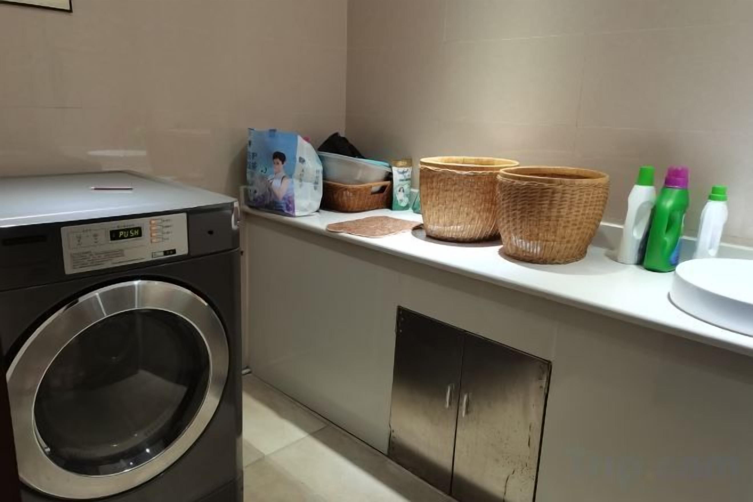 A laundry area with a washing machine, baskets, and cleaning supplies.