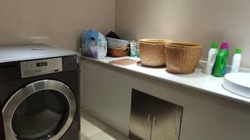 A laundry area with a washing machine, baskets, and cleaning supplies.