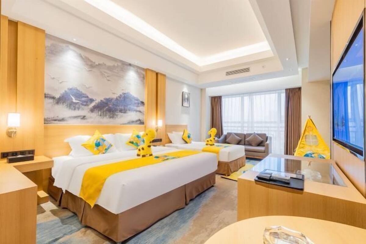 A hotel room with a large bed, a desk, a television, and a painting on the wall.