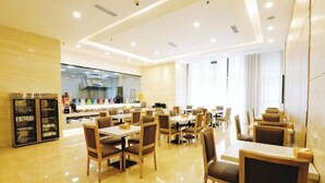 A modern restaurant with a clean, bright interior, featuring wooden tables and chairs, a kitchen area in the background, and large windows allowing natural light. - Tianyue Hotel (Chengdu)
