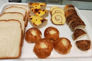 A tray with various food items including bread, pastries, and a slice of cake. - Tianyue Hotel (Chengdu)