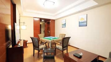 A hotel room with a dining table, chairs, a television, and artwork on the walls.