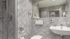 A modern bathroom with a shower, toilet, sink, and a mirror. - Hotel AM Schlosspark (Ismaning)