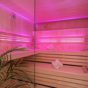 Un sauna avec des bancs en bois et un éclairage rose.