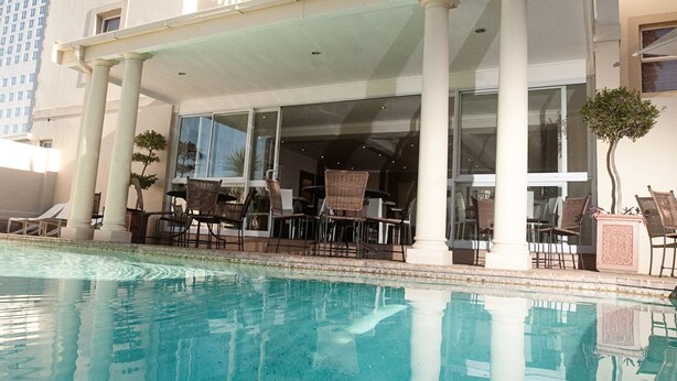 Ein Hotel mit Poolbereich, Außenbereich zum Sitzen und einer überdachten Terrasse.