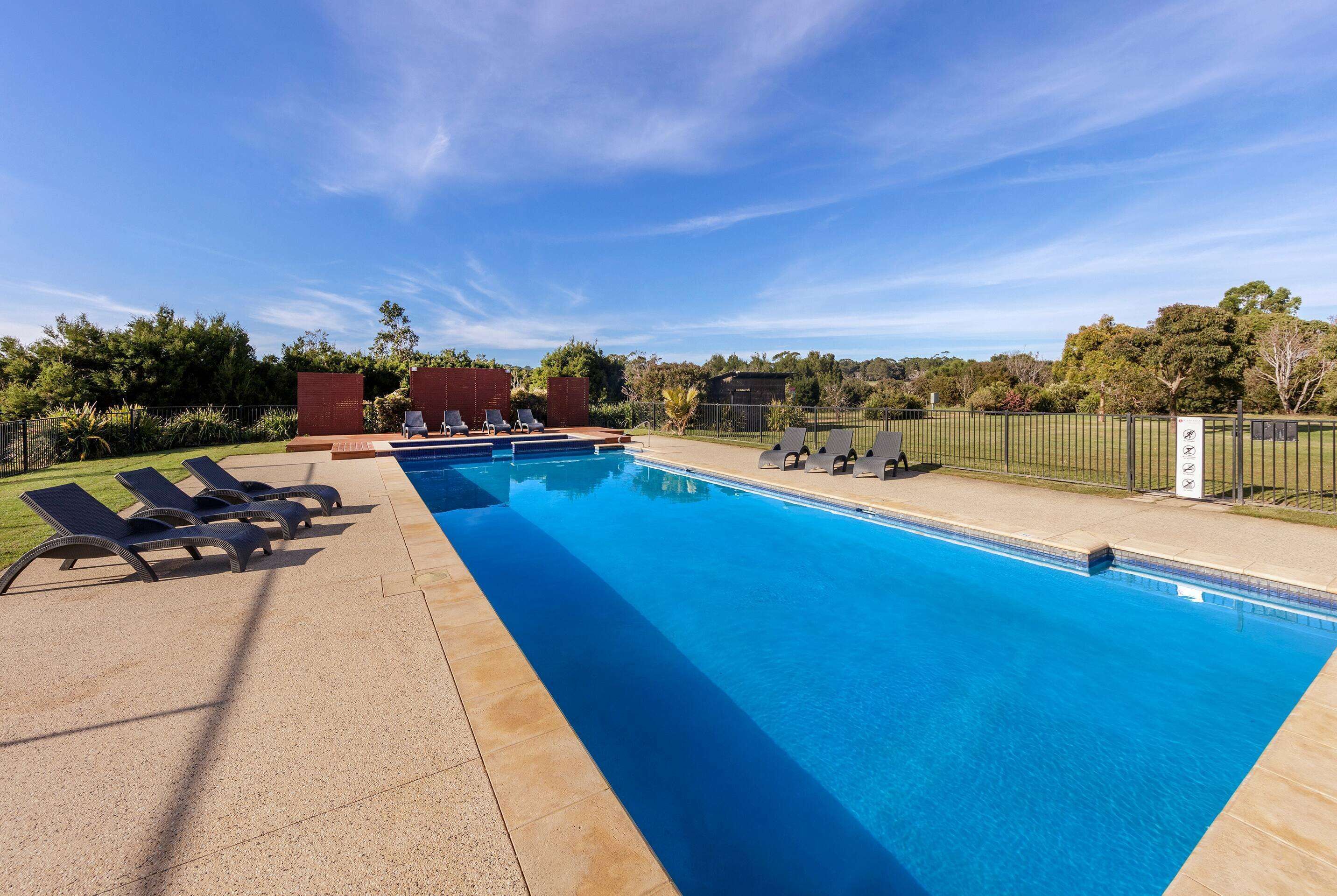 A swimming pool with lounge chairs and a fenced area.