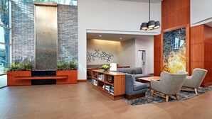 Eine moderne Lobby mit einer Wand aus Stein, Holzmöbeln und einer Sitzecke mit Blick ins Freie.