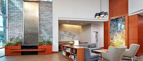 Un vestíbulo moderno con una pared de acento de piedra, muebles de madera y un área de descanso con vistas al exterior.