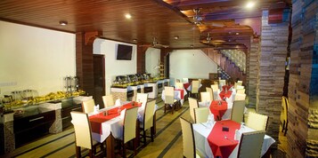 A restaurant with multiple tables, a bar area, and a staircase leading to an upper level.