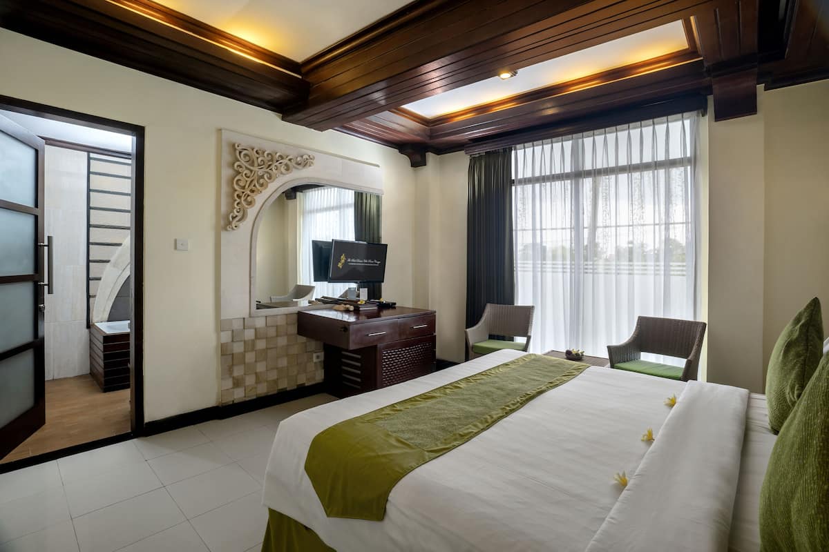 A hotel room with a bed, a desk, a chair, and a TV.