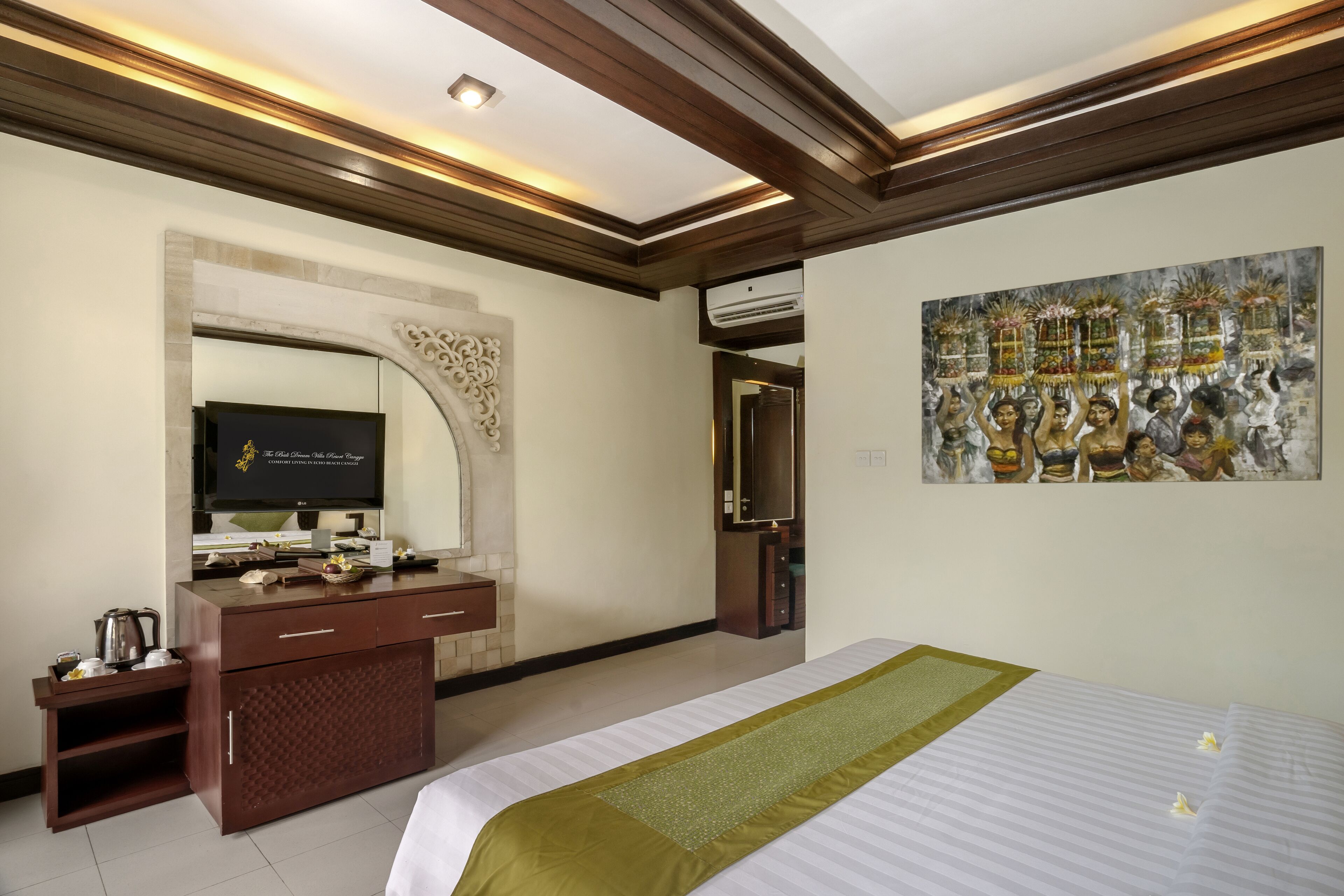 A hotel room with a bed, a wooden dresser, a television, and a painting on the wall.