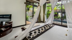 A bedroom with a bed, a TV, a desk, and a view of a pool and greenery. - The Bali Dream Villa Resort Echo Beach Canggu (Pererenan)