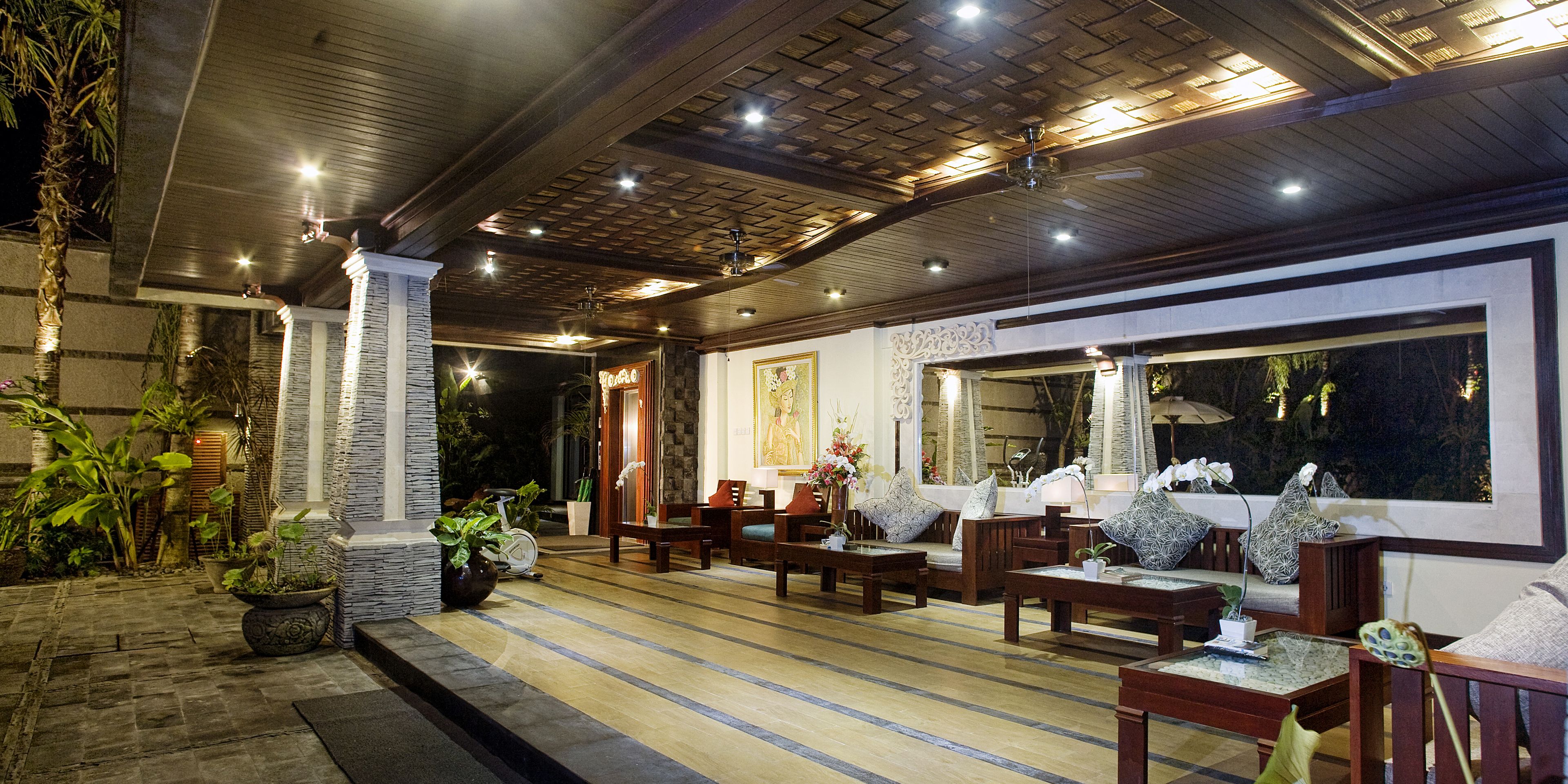 An indoor seating area with wooden furniture, a large window, and decorative plants.