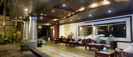 An indoor seating area with wooden furniture, a large window, and decorative plants.