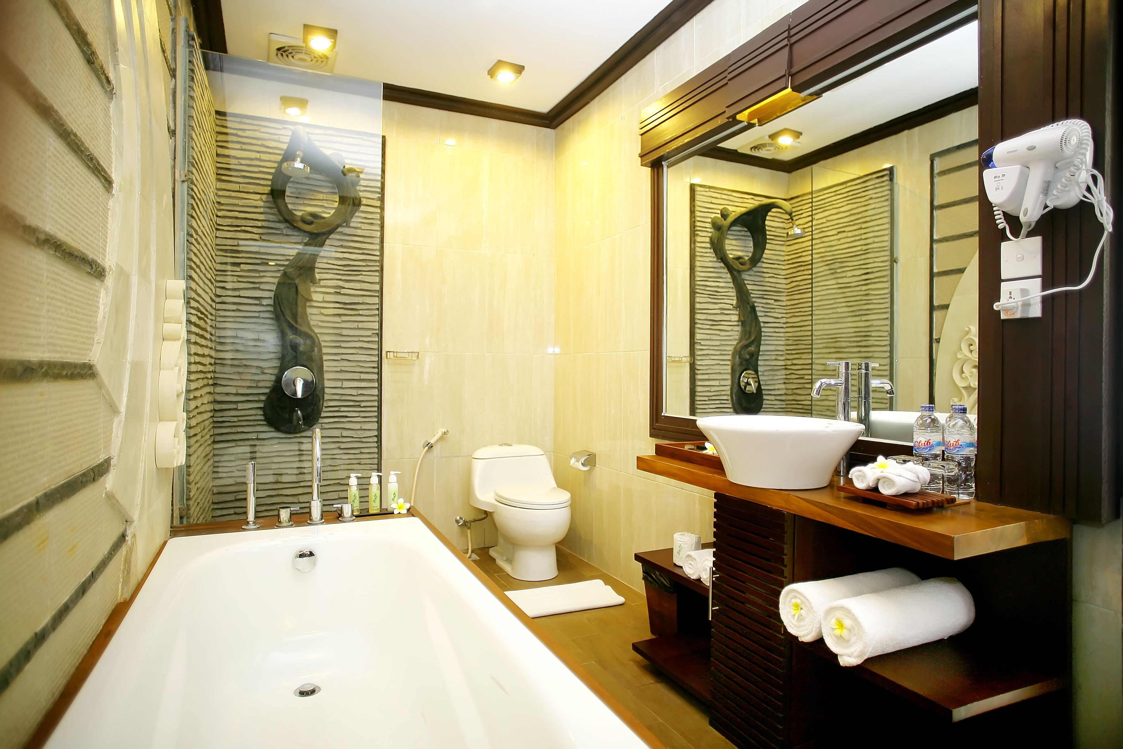 Ein modernes Badezimmer mit einer großen Badewanne, einer Toilette und einem Waschtisch inklusive Waschbecken und Spiegel.