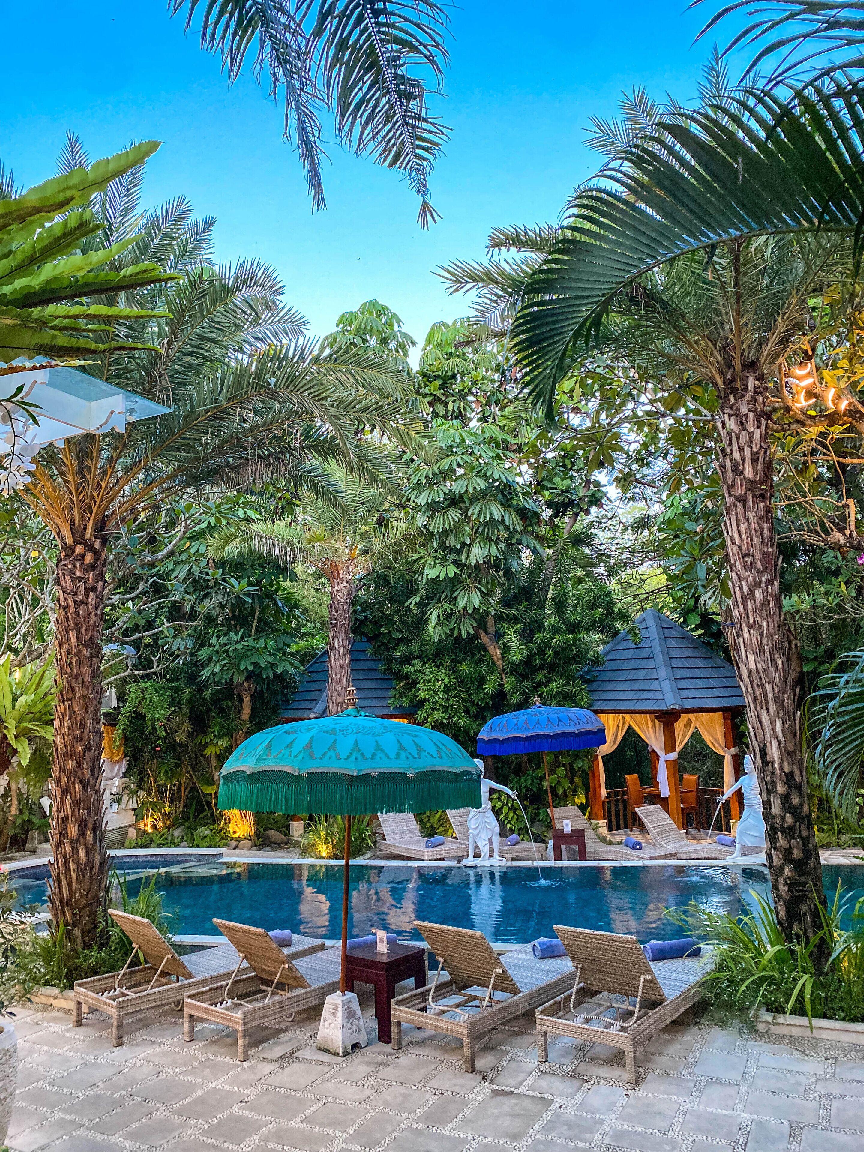 A pool area with lounge chairs, umbrellas, and a gazebo.