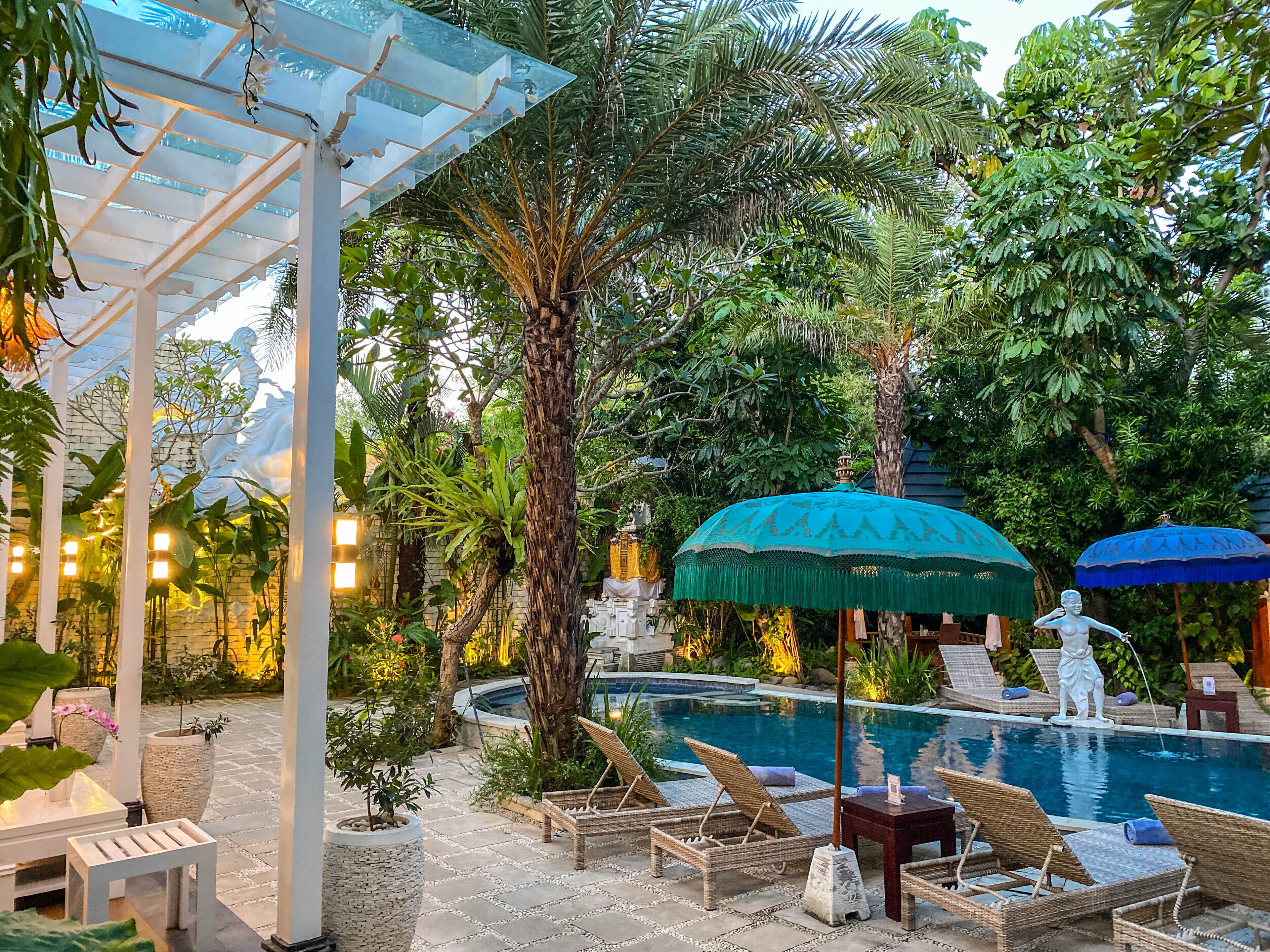 A pool area with lounge chairs, umbrellas, and a pergola.