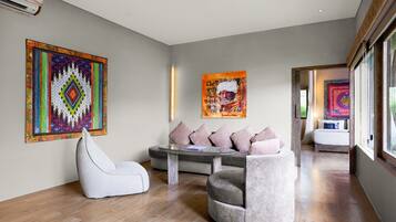 A modern living room with a sofa, a chair, and two artworks on the wall.