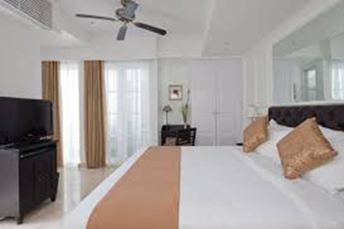 Une chambre d’hôtel avec un lit, une télévision, un ventilateur de plafond et une fenêtre avec des rideaux.