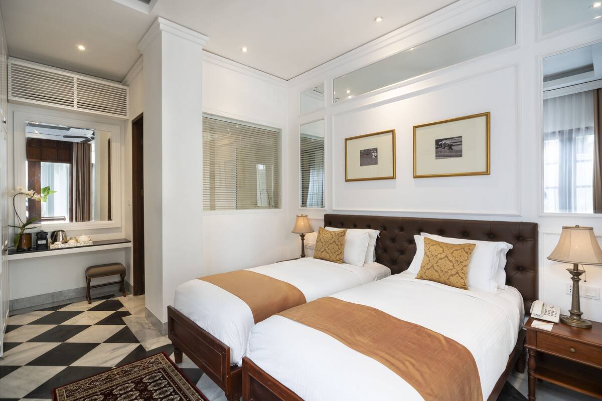 Une chambre d’hôtel avec deux lits, un bureau et un miroir.