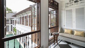 Un balcon donnant sur un bâtiment traditionnel, un canapé blanc avec des coussins et une petite table avec des livres.